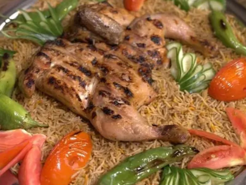 A Sufraq grilled chargha platter brought to the centre of the table, with seasoned rice and signature sauces
